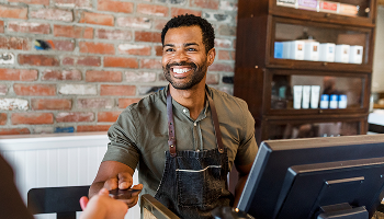 A cheerful man is positioned behind a counter, ready to assist customers